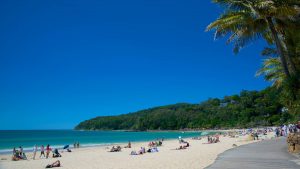 Plage idyllique de Noosa Heads en Australie avec palmiers, sable fin blanc, eau couleur azur et ciel bleu