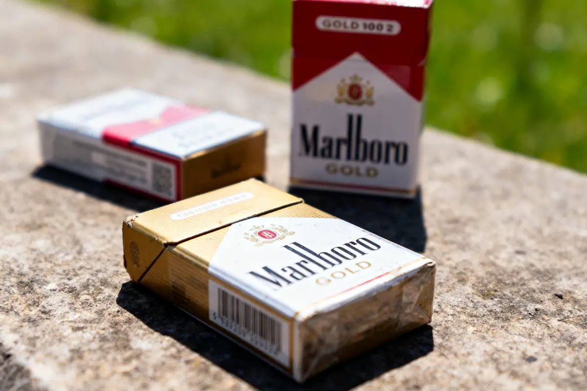 Trois paquets de cigarettes Marlboro Gold en extérieur sur une surface en pierre.