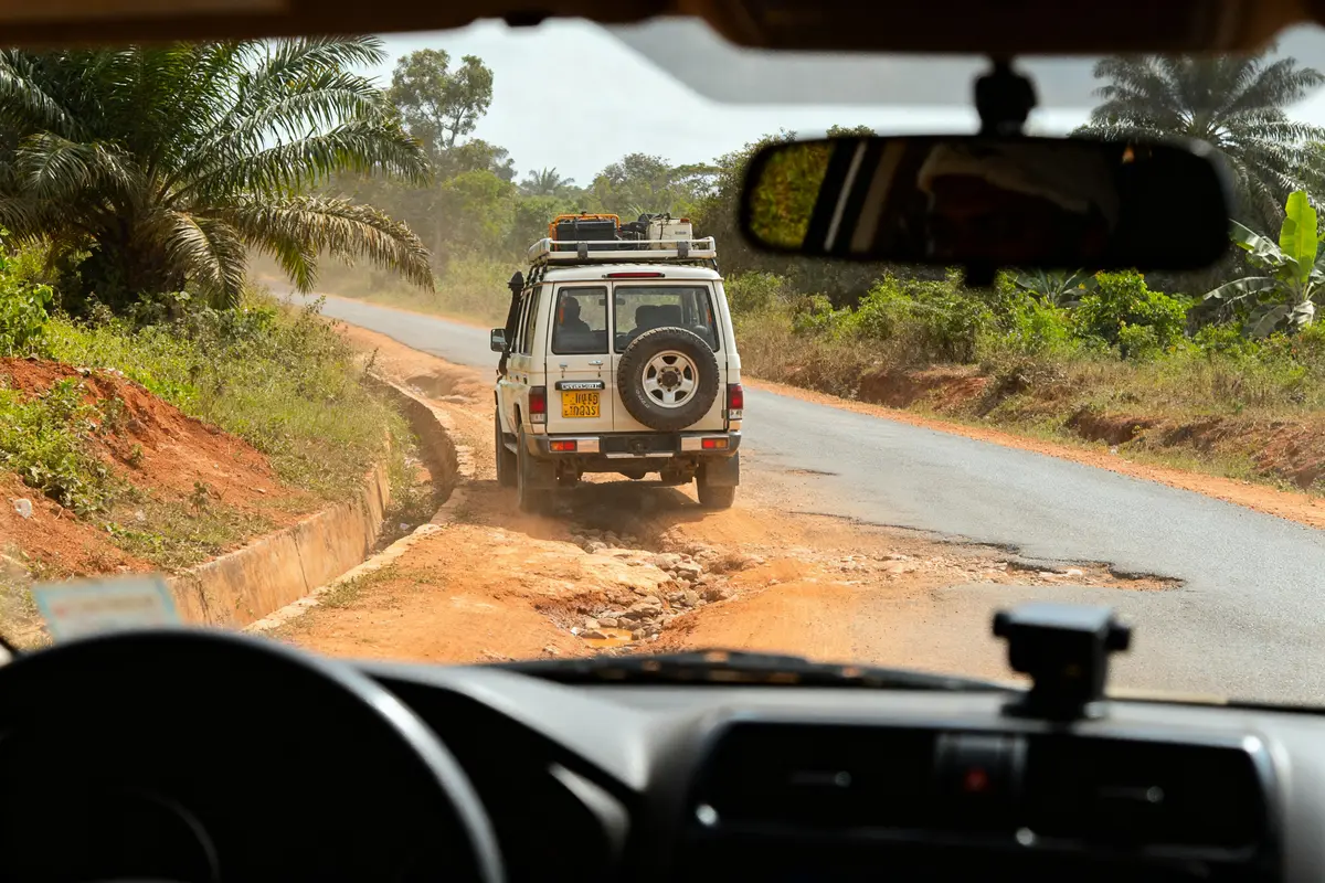 Vue intérieure de voiture suivant un 4x4 sur une route de campagne dérassi poussiéreuse