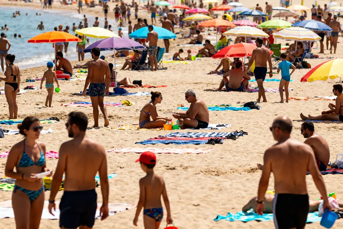 Personnes sous parasols colorés sur une plage à éviter au Cap d'Agde
