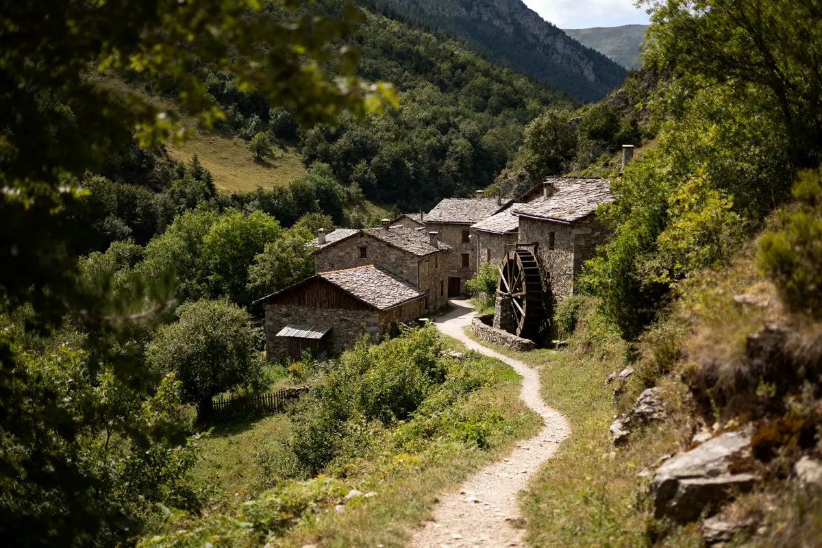 Vue d'un village pittoresque avec moulin à eau entouré de verdure à Urdues