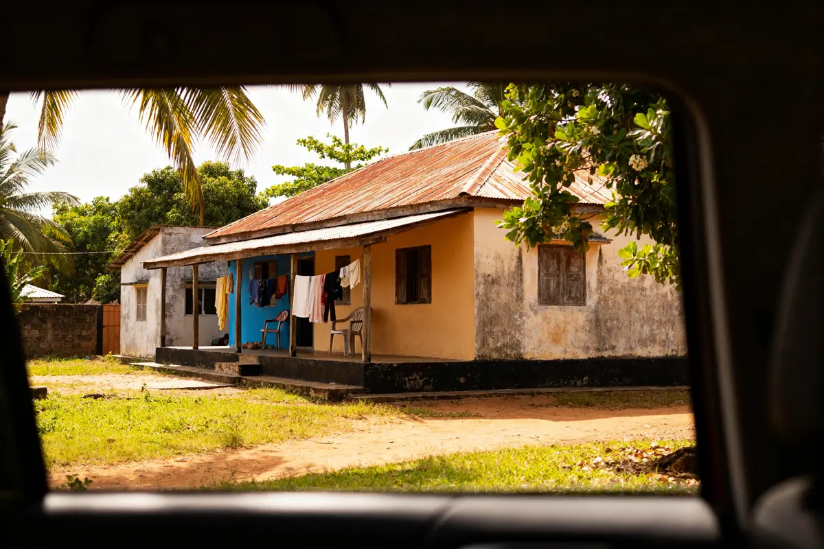 Vue extérieure d'une maison traditionnelle aux Comores entourée de palmiers et de verdure